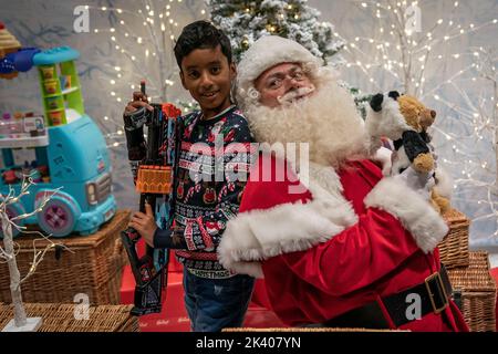 Adam Baba, 9, und ein Mann, der als Weihnachtsmann gekleidet war. Während Kinder an der Hamleys Christmas Showcase 2022 teilnehmen, bei der die 10 besten Spielzeuge für Weihnachten in der Regent Street, London, präsentiert werden. Bilddatum: Donnerstag, 29. September 2022. Stockfoto