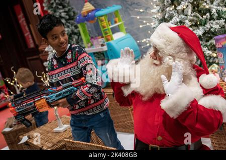 Adam Baba, 9, und ein Mann, der als Weihnachtsmann gekleidet war. Während Kinder an der Hamleys Christmas Showcase 2022 teilnehmen, bei der die 10 besten Spielzeuge für Weihnachten in der Regent Street, London, präsentiert werden. Bilddatum: Donnerstag, 29. September 2022. Stockfoto