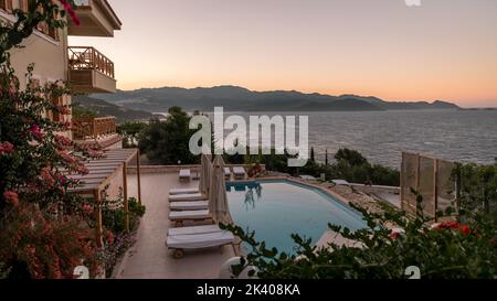 Liegestühle mit weißen Sonnenschirmen mit Blick auf das Meer in der Türkei an einem Sommertag, Liegen auf Felsen mit Blick auf das Meer Stockfoto