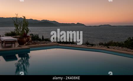 Liegestühle mit weißen Sonnenschirmen mit Blick auf das Meer in der Türkei an einem Sommertag, Liegen auf Felsen mit Blick auf das Meer Stockfoto