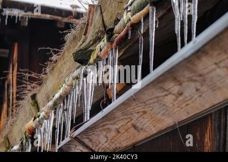 Eisstalaktiten schmelzen im Frühjahr in einer Dachrinne Stockfoto