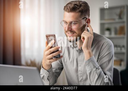 Schöner bärtiger Student hört Online-Kurs, glücklich lächelnden Mann verwenden Kopfhörer zu studieren, ebook Konzept Stockfoto
