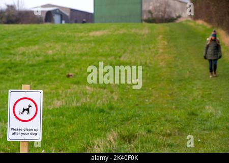 Melden Sie sich an einem öffentlichen Wanderweg auf Ackerland für Hundewanderer, um nach ihrem Haustier aufzuräumen Stockfoto