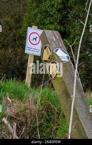 Zwei Schilder, darunter ein einstürzender Posten mit Pfeilen zum öffentlichen Fußweg Stockfoto