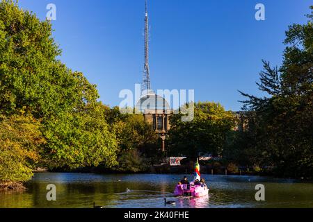 Eine orthodoxe jüdische Familie, die sich in einem ungewöhnlichen Paddelboot auf dem Alexandra Park See im Norden Londons amüsieren kann.der BBC Tower ist deutlich zu sehen. Stockfoto