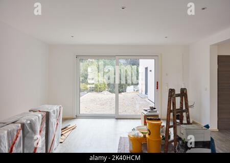 Großes Zimmer mit Möbeln nach der Renovierung mit Terrassentür, bevor man in ein neues Haus zieht Stockfoto