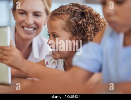 Tablet, junges Mädchen sehen Zeichentrickfilme, Musik streamen und online surfen zu Hause. Eltern, Großmutter oder Babysitter mit Lächeln und glückliche Kinder oder Stockfoto