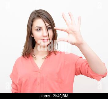 Frau zeigt kleine Menge von etwas mit Fingern, isoliert auf weißem Stockfoto Stockfoto