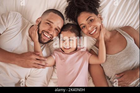 Familie glücklich, Kind und oben Bett mit den Eltern am Morgen, lustige Gesicht im Haus und entspannen nach dem gemeinsamen Schlafen in zu Hause. Porträt einer glücklichen Mutter Stockfoto