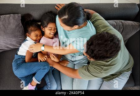 Komische Familie, fröhliches Sofa und kinderliebe Eltern auf der Wohnzimmercouch, kitzeln für Comedy und lächeln gemeinsam in der Lounge. Mädchen Kinder lachen Stockfoto