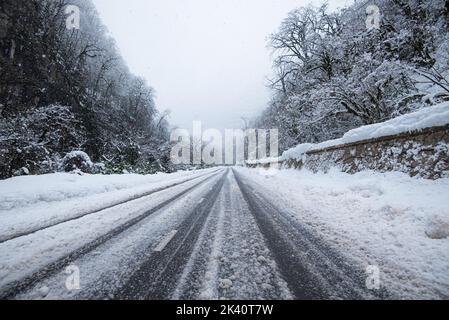 Straße im Wald mit bedecktem Schnee. Winterzeit. Landschaft. Schneebedeckte Bergwaldstraße Stockfoto