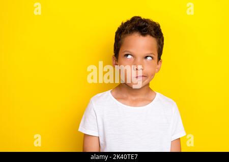 Foto von Minded kleinen Jungen stilvolle männliche Person suchen leeren Raum unsicher wollen neue Outfit isoliert auf gelbem Hintergrund Stockfoto