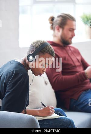 Studentin, schwarze Frau mit Musik, die im Notizbuch für den Zeitplan, die Planung oder das Lernen beim Hören von Podcast oder Radio geschrieben wird. Denken, studieren oder Stockfoto