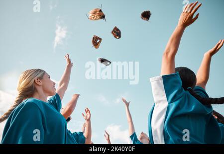 Siegerteam, Sportfest und Baseballfrauen werfen Handschuhe in die Luft für den Torsieg und fühlen sich nach dem Spiel oder Spiel glücklich. Teamarbeit Stockfoto