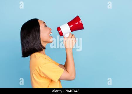 Foto-Porträt von niedlichen jungen Frau chinesischen lächelnden Schrei Megaphon haben Spaß gekleidet stilvolle gelbe Look isoliert auf blauem Hintergrund Stockfoto