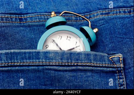 Blauer Wecker in blauer Jeans-Tasche Stockfoto