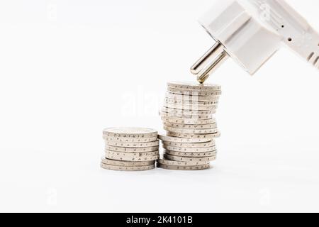 Stapel aufsteigender Münzen und elektrischer Stecker. Konzept der steigenden Strompreise Stockfoto