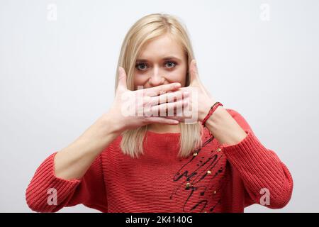 Frau macht eine leisende Geste, indem sie ihren Finger auf ihre Lippen hebt, während sie um Schweigen bittet oder um deine Hilfe bei der Aufbewahrung eines geheimen Stockfotos Stockfoto