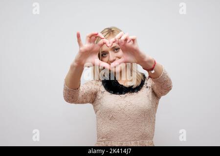 Frau zeigt Hände Herz auf weißem Hintergrund Stockfoto