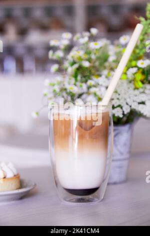 Ästhetischer Eislatte im Café. Schlechtes Vergnügen, Kaffeezeit. Vertikales Foto. Stockfoto