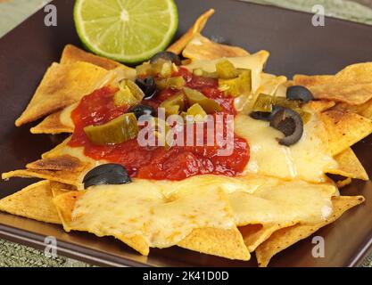 Knusprige, kitschige Nachos mit Tomaten-Salsa-Oliven und Jalapenos Stockfoto
