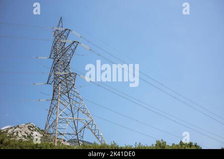 Hochspannungsleitungen und Masten auf blauem Himmel. Metallmast mit Transformatorleitung. Elektrische Energieübertragung Stockfoto