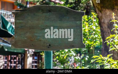 Holz vintage leere Schild auf Stange für Text oder Werbung, auf Unschärfe Natur und Gebäude Hintergrund. Leerer Wegweiser, Plakatwand, Kopierraum Stockfoto