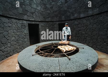 Timanfaya-Nationalpark, Spanien - 24. April 2022: Kochen Sie das Grillhähnchen bei vulkanischer Hitze im Restaurant El Diablo Stockfoto