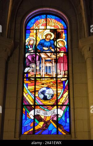 Spanien, Madrid. Kathedrale von Almudena. Modernes Buntglasfenster. "Er war der Sohn eines Arbeiters" in Latein. Stockfoto