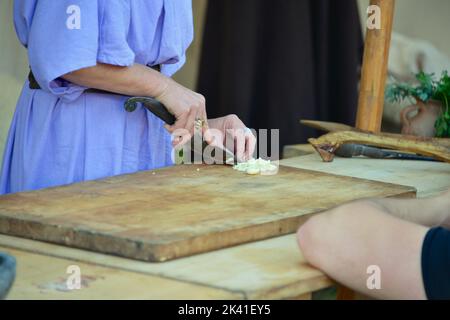 Der Koch schneidet die Zwiebeln auf einem Holzbrett Stockfoto