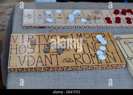 Ein römischer Knochenwürfel und ein Spieltisch auf einem Holztisch Stockfoto
