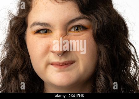 Junge Frau, die die Kamera anschaut, mit verschwinkter Nase Stockfoto