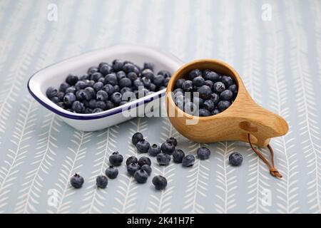 Kuksa (finnische Holzkrug) und frische Heidelbeeren Stockfoto