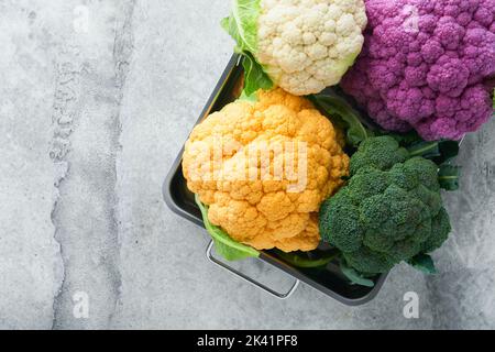 Colorfu-Blumenkohl. Verschiedene Arten von Blumenkohl auf grauem Beton Hintergrund. Violette, gelbe, weiße und grüne Farbkabbage. Brokkoli und Romanesco. Stockfoto