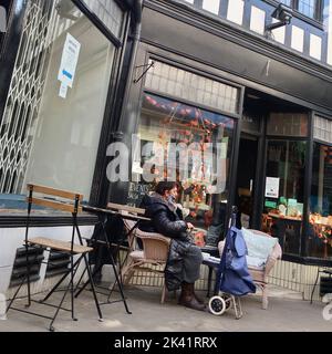 Ipswich, Suffolk, Großbritannien - 29. September 2022 : strahlender sonniger Herbstnachmittag im Stadtzentrum. Eine Frau, die sich vor einem Café ausruhte. Stockfoto