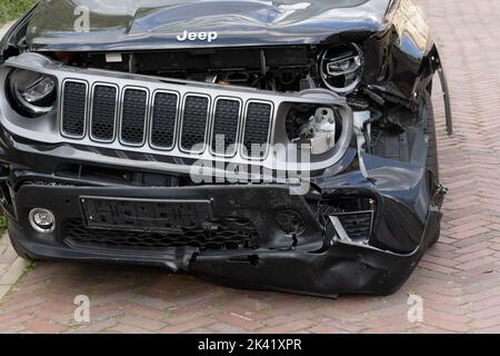 Jeepwagen mit Frontalschaden durch einen Autounfall, schwarzes Geländefahrzeug mit gebrochenem Stoßfänger, Scheinwerfer, verbogene Motorhaube. Stockfoto