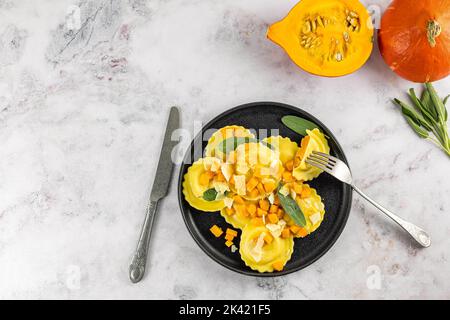 Saisonales Herbstrezept. Kürbisravioli mit Salbei, Parmesan und Olivenöl. Stockfoto