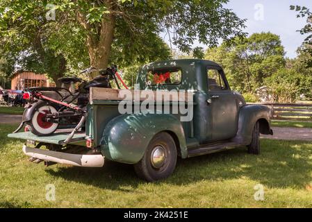 FLINT, MI/USA - 22. JUNI 2019: Ein Chevrolet 3100 Truck und Motorrad aus dem Jahr 1953, Sloan Museum Auto Fair, Crossroads Village, in der Nähe von Flint, Michigan. Stockfoto