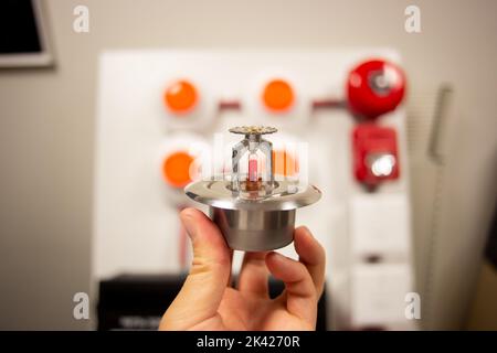 Feueralarm und Scheinsprinkleranlage, die an einer weißen Wand befestigt ist, die für Schulungen verwendet wird Stockfoto