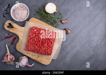 Hackfleisch liegt auf einem Schneidebrett, umgeben von Kochzutaten. Stockfoto