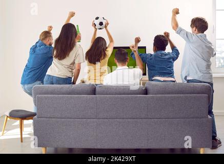 Rückansicht von Sportfans, die auf der Couch sitzen und Fußballspiele im Fernsehen anschauen und sich über den Sieg freuen. Stockfoto