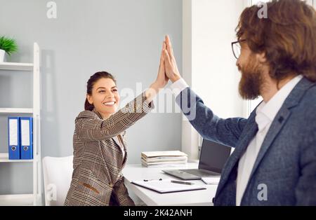 Freudig positive Kollegen im Büro geben sich nach dem Job Gut gemacht. fünf hoch Stockfoto