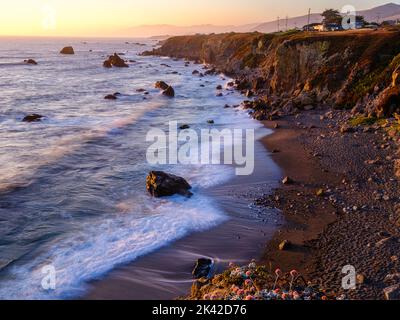 Ein romantischer Blick entlang der Küste der Bucht von Bodgea; sonnenverwöhnte Wellen bei Sonnenuntergang. Stockfoto