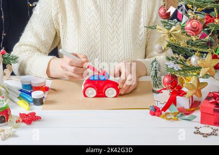 Schritt-für-Schritt Foto-Anleitung für Weihnachten Dekor - ein Mädchen malt eine Gipsmaschine, Schritt 3 - Färben des Körpers mit einem Filzstift Stockfoto