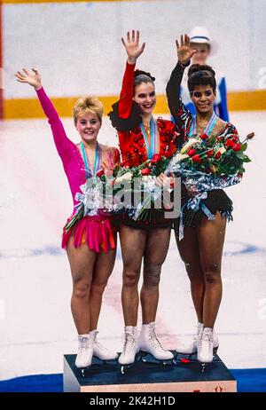 Katarina Witt (DDR) Goldmedaillengewinnerin und Olympiasiegerin mit Elizabeth Manley (CAN)-L- Silbermedaillengewinnerin und Bronzemedaillengewinnerin Debi Thomas (USA) beim Damen-Eiskunstlauf bei den Olympischen Winterspielen 1988. Stockfoto