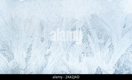 Hintergrund des Eismusters. Kalter Winter. Weihnachtswunder. Äußerster Norden. Abstrakte dekorative Frost Schneeflocken Kristalle Tracery auf gefrorenen weiß blauen Fenster Stockfoto