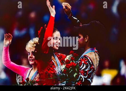 Katarina Witt (DDR) Goldmedaillengewinnerin und Olympiasiegerin mit Elizabeth Manley (CAN)-L- Silbermedaillengewinnerin und Bronzemedaillengewinnerin Debi Thomas (USA) beim Damen-Eiskunstlauf bei den Olympischen Winterspielen 1988. Stockfoto