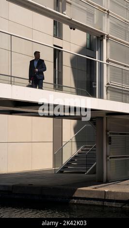 Ein Geschäftsmann in Silhouette, der eine Brücke vom Bürogebäude über den Grand Union-Kanal im Nordwesten Londons überquert Stockfoto