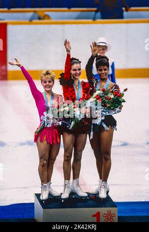 Katarina Witt (DDR) Goldmedaillengewinnerin und Olympiasiegerin mit Elizabeth Manley (CAN)-L- Silbermedaillengewinnerin und Bronzemedaillengewinnerin Debi Thomas (USA) beim Damen-Eiskunstlauf bei den Olympischen Winterspielen 1988. Stockfoto