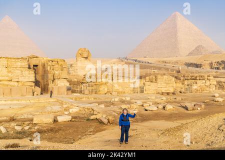 Gizeh, Kairo, Ägypten. 18. Februar 2022. Tourist hält ihr Telefon vor der Großen Sphinx und den Großen Pyramiden in Gizeh hoch. Stockfoto